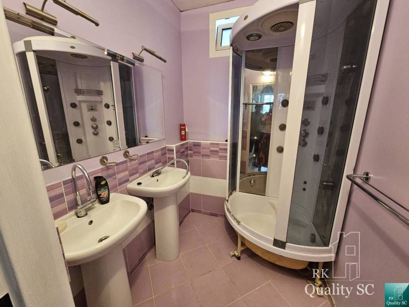 Badezimmer in einer 2-Zimmer-Wohnung mit zwei Waschbecken und einer Hydromassagedusche.