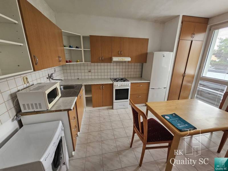 Küche in einer 2-Zimmer-Wohnung mit Holzschränken und Esstisch.