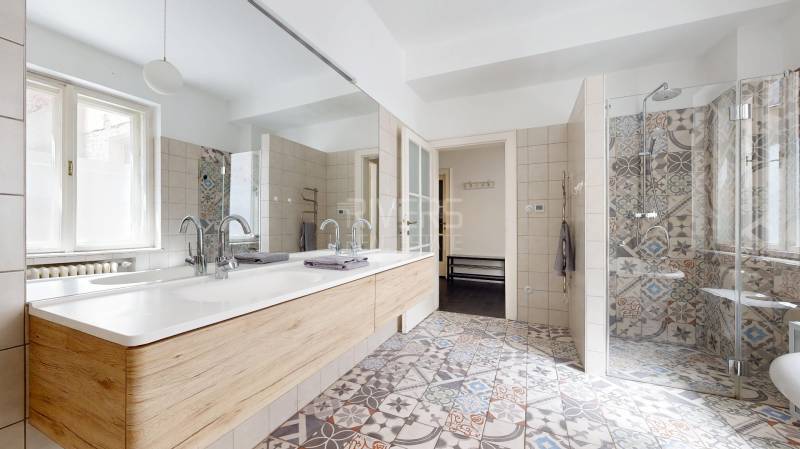 Badezimmer mit Doppelwaschbecken, Duschkabine und gemusterten Fliesen in einer 3-Zimmer-Wohnung.