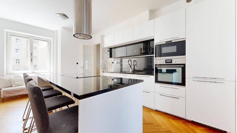 Küche in einer 3-Zimmer-Wohnung mit Insel, weißen Schränken und eingebauten Geräten.