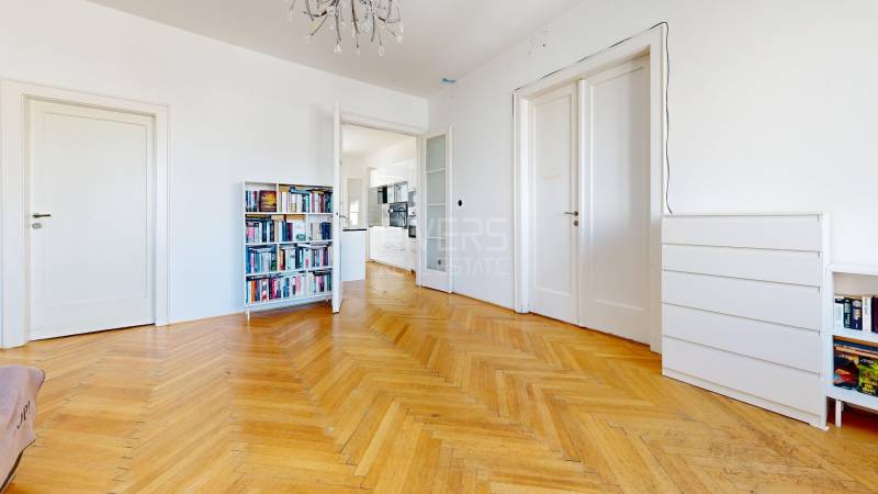 Ein geräumiges Zimmer in einer 3-Zimmer-Wohnung mit Bibliothek, Parkettboden und weißen Türen.