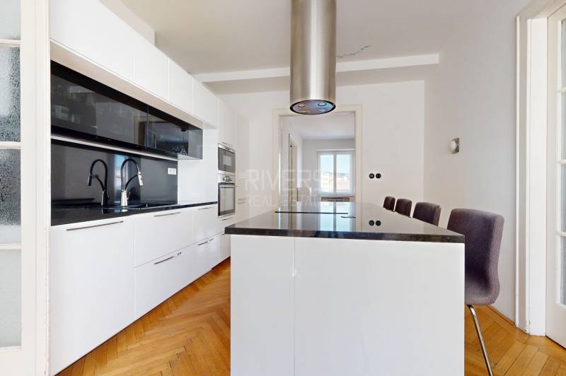 Küche in einer 3-Zimmer-Wohnung mit einer schwarzen Kücheninsel und weißen Schränken.