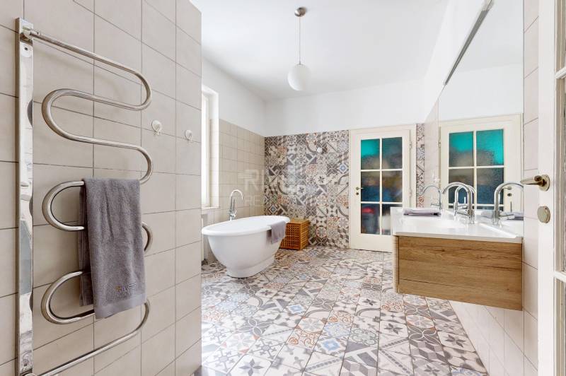 Badezimmer in einer 3-Zimmer-Wohnung mit bunten Fliesen, Badewanne und Doppelwaschbecken.