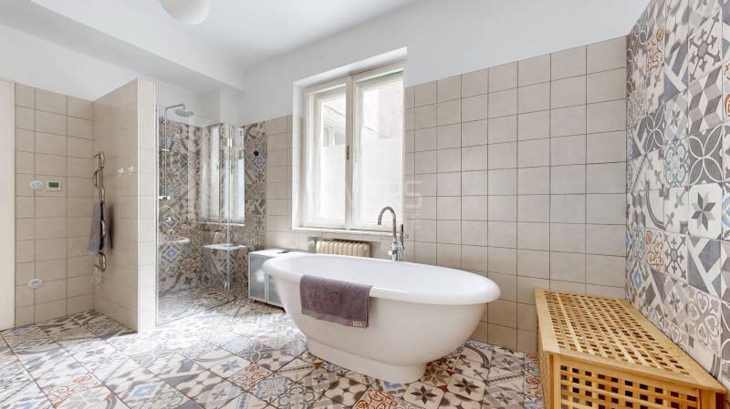 Badezimmer mit Duschkabine, freistehender Badewanne und dekorativen Fliesen in einer 3-Zimmer-Wohnung.