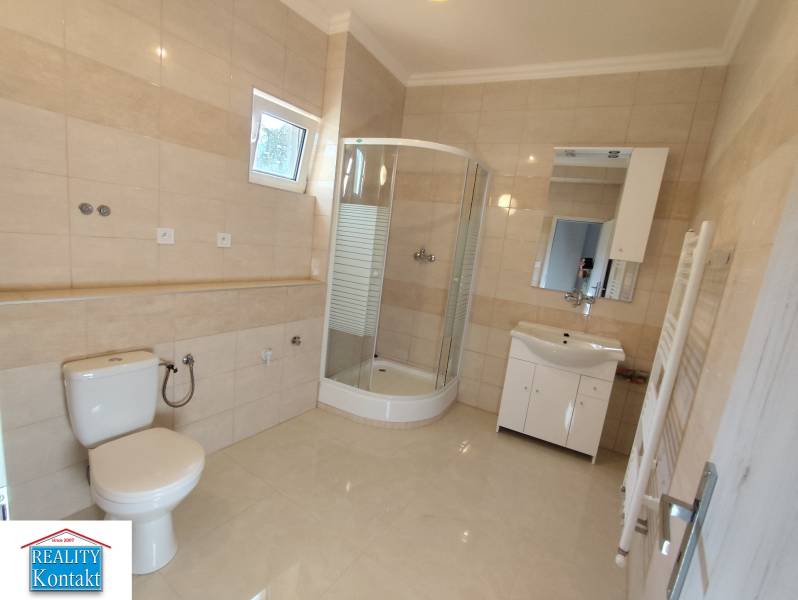 Badezimmer in einer Einzimmerwohnung mit Dusche, Waschbecken, Toilette und Fliesen.
