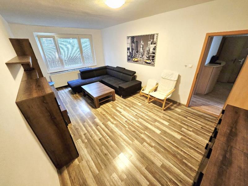 Wohnzimmer in einer 3-Zimmer-Wohnung mit einem Sofa, einem Sessel und einem Bild an der Wand.