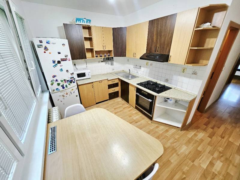 Küche in einer 3-Zimmer-Wohnung mit Herd, Kühlschrank und Holztisch.