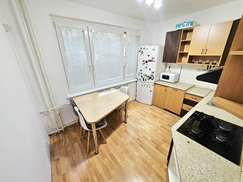 Küche mit Herd, Kühlschrank und Tisch in einer 3-Zimmer-Wohnung.