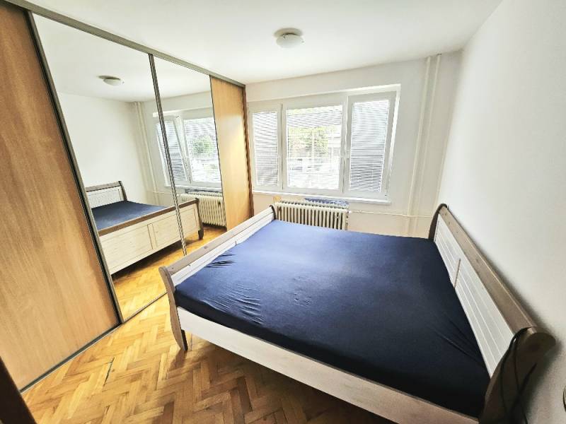 Schlafzimmer in einer 3-Zimmer-Wohnung mit Holzboden, großem Schrank und Bett.