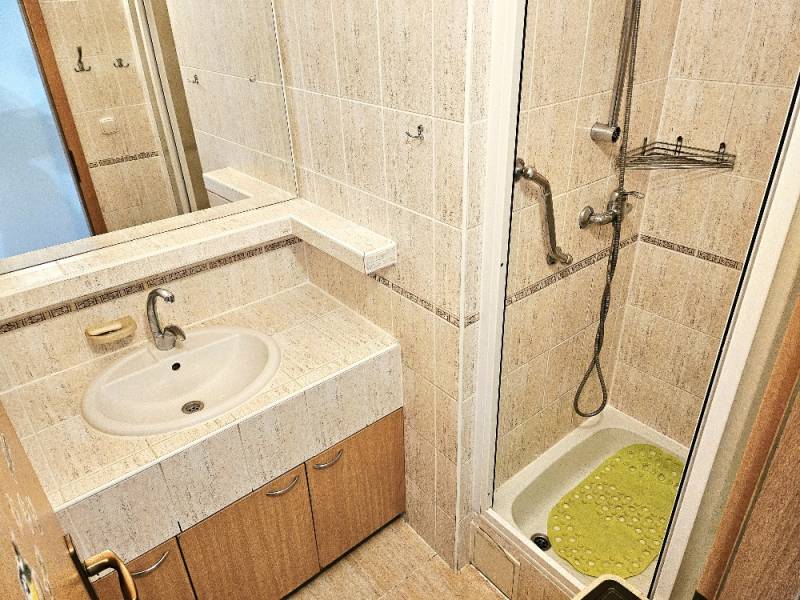 Badezimmer mit Waschbecken, Duschkabine und Fliesen in einer 3-Zimmer-Wohnung.