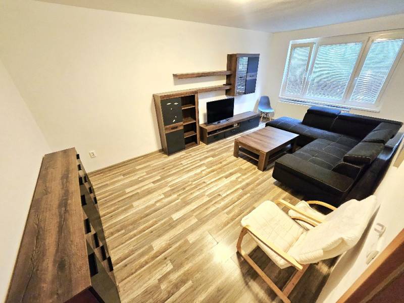 Wohnzimmer in einer 3-Zimmer-Wohnung mit dunklem Sofa und Holzmöbeln.
