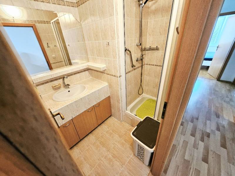Badezimmer mit Dusche in einer 3-Zimmer-Wohnung, helle Fliesen und Spiegel.