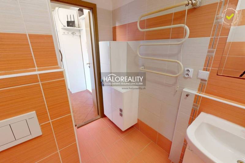 Badezimmer in einer 4-Zimmer-Wohnung mit orangefarbenen Fliesen und einem Handtuchtrockner.