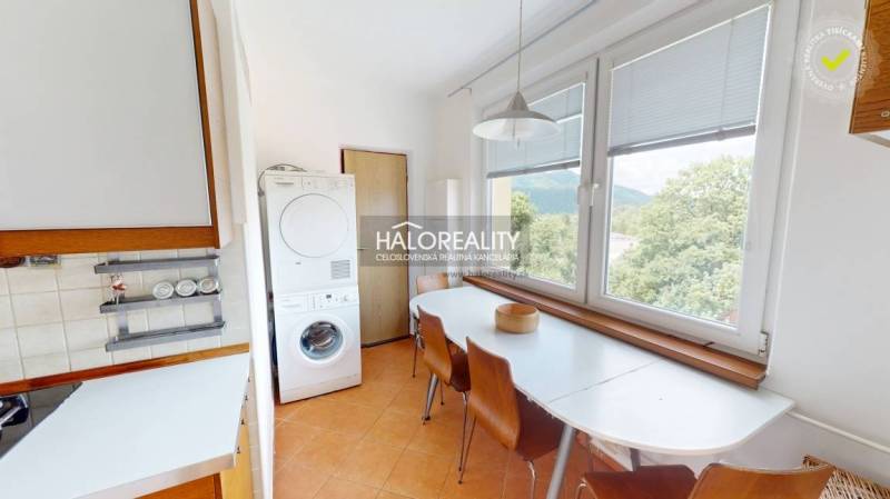 Die Küche in der 4-Zimmer-Wohnung enthält einen Esstisch, Stühle und eine Waschmaschine.