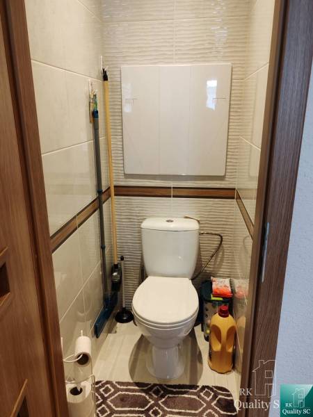 Toilette in einer 3-Zimmer-Wohnung mit Stauraum für Reinigungsmittel.