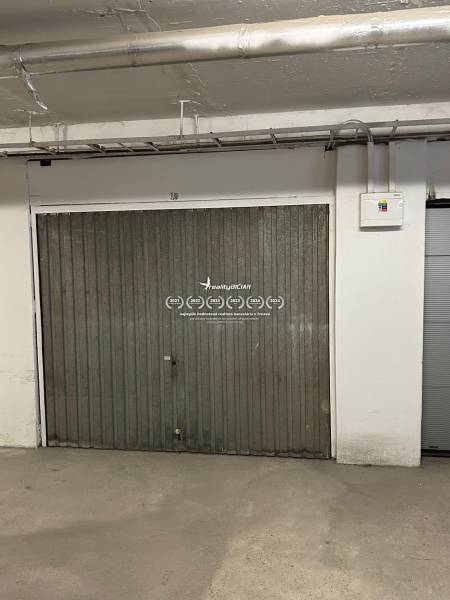 Metalltür in der Garage mit Rohrleitungen und einem Elektroschaltkasten an der Wand.