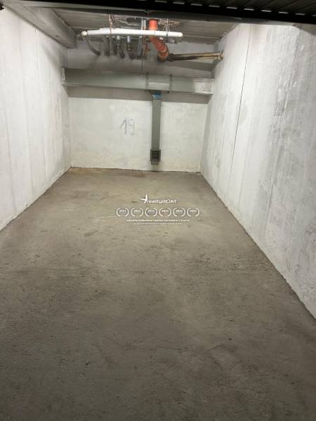 Geschlossener Garagenraum mit Betonboden und weißen Wänden, Nummer 19, Rohre an der Decke.