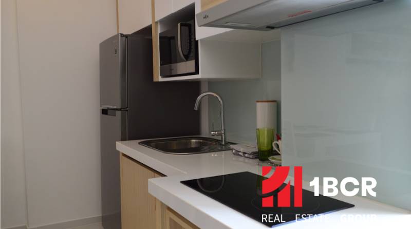 Küche in einer 2-Zimmer-Wohnung mit Spüle, Kochfeld und Mikrowelle.