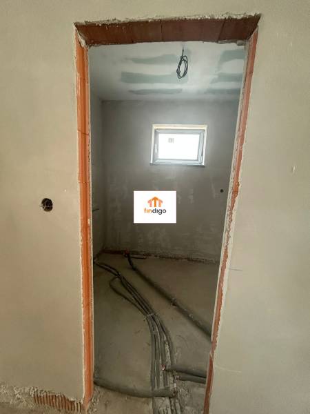 Unvollendetes Zimmer in einem Einfamilienhaus mit Fenster und vorbereiteter Elektroinstallation.