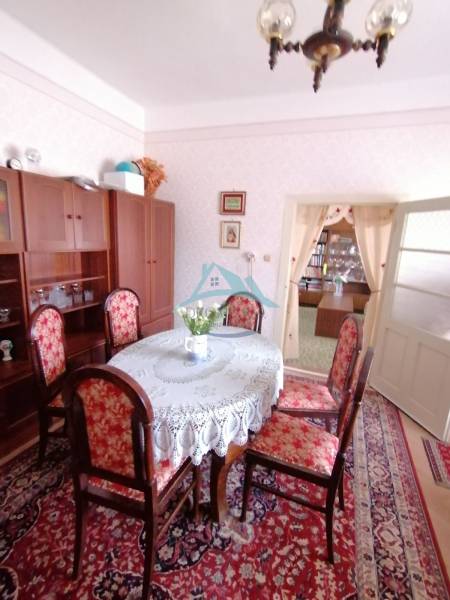 Esszimmer in einem Einfamilienhaus mit antiken Möbeln, einem Blumenmusterteppich und heller Dekoration.