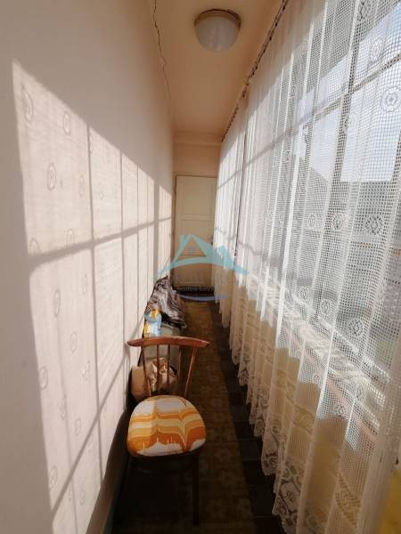 Ein enger Flur mit Spitzenvorhängen und einem Sessel in einem Einfamilienhaus.