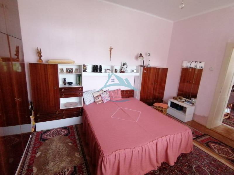 Schlafzimmer mit Holzmöbeln und rosa Bettwäsche in einem Einfamilienhaus.