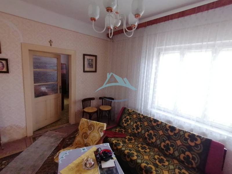 Ein Zimmer mit einem Vintage-Sofa, Möbeln und Vorhängen in einem Einfamilienhaus.