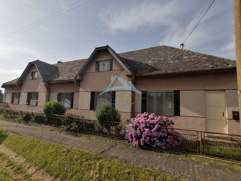 Ein Einfamilienhaus in Hrkovce mit Blumen vor dem Zaun und einem Schrägdach.