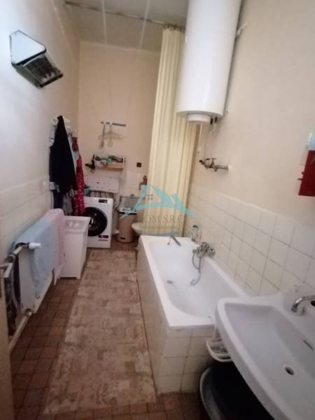 Badezimmer in einem Einfamilienhaus mit Badewanne, Waschbecken und Waschmaschine.