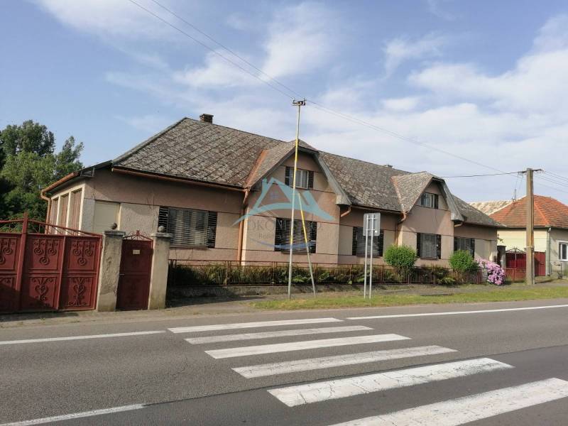 Ein Einfamilienhaus in Hrkovce an der Straße, mit Ziegeldach, geschlossene rote Tore.
