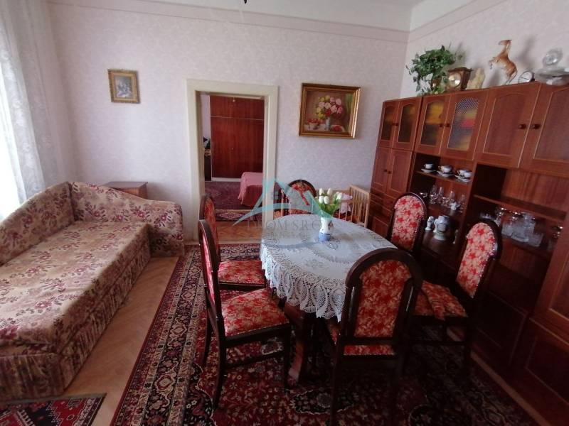 Wohnzimmer in einem Einfamilienhaus mit Sofa, Esstisch und Vitrine.