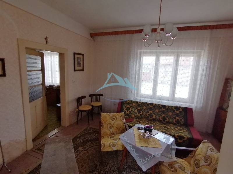 Wohnzimmer in einem Einfamilienhaus mit Retro-Möbeln, gemusterten Vorhängen und sanfter Beleuchtung.