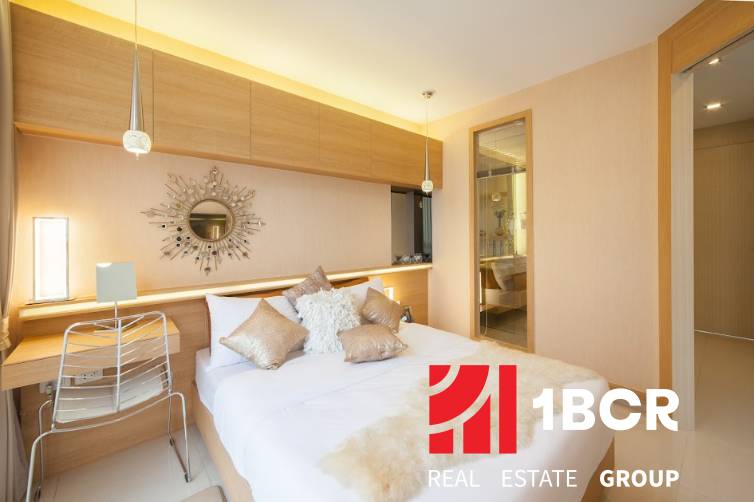 Helles Schlafzimmer in einer 2-Zimmer-Wohnung mit dekorativem Spiegel über dem Bett.