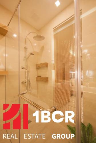 Duschkabine mit Holzregalen in einer 3-Zimmer-Wohnung, verziert mit dem Gütesiegel der Immobilienagentur.