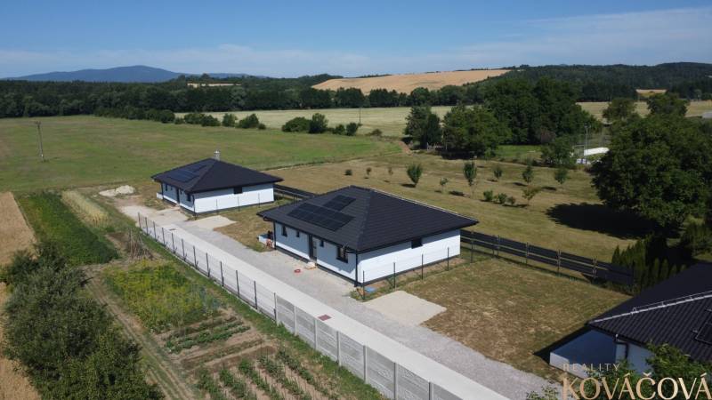 Einfamilienhäuser in Podlužany mit modernen Dächern und Sonnenkollektoren auf dem Feld.