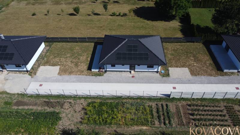 Einfamilienhäuser in Podlužany mit Solarpaneelen, Rasen und Garten.