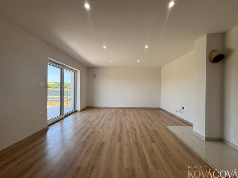 Ein geräumiger Raum mit Holzboden und einem großen Fenster in einem Einfamilienhaus.