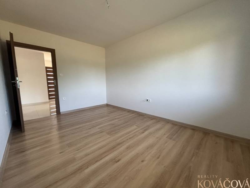 Ein leerer Raum in einem Einfamilienhaus mit Holzboden und weißen Wänden.