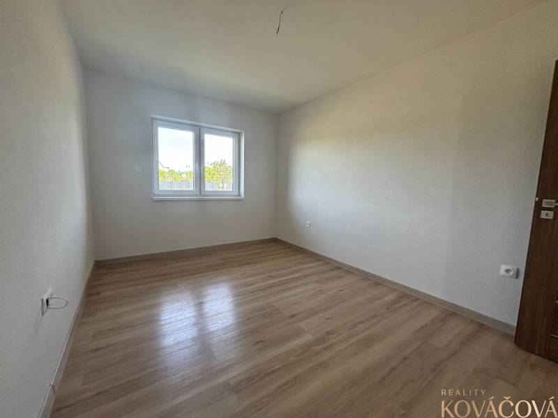 Ein leerer Raum mit Holzboden und einem Fenster in einem Einfamilienhaus.