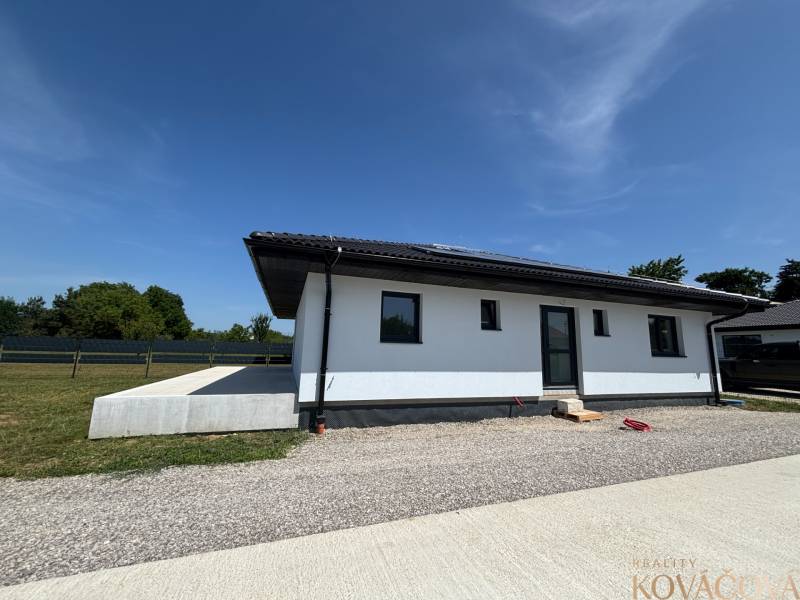 Ein Einfamilienhaus in Podlužany mit einem Rasen-Grundstück und einer Kieszufahrtsstraße.