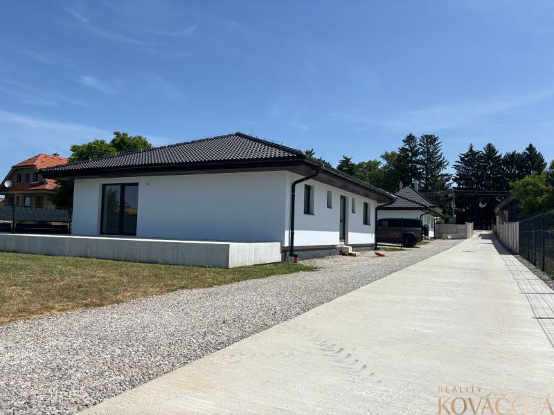 Einfamilienhaus in Podlužany mit weißer Fassade, schrägem Dach und großer Zufahrt.