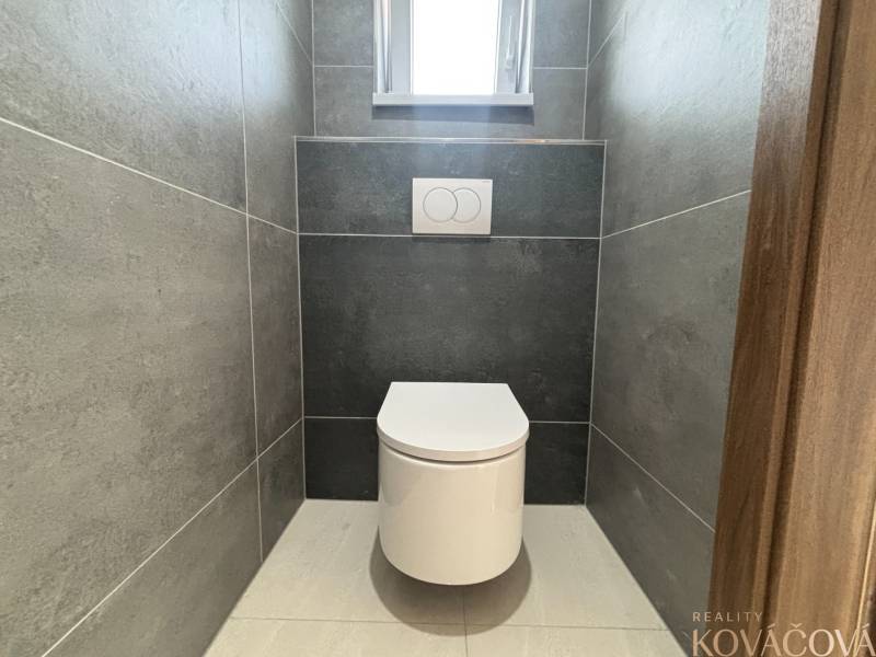 Toilette mit Fliesen in einem Einfamilienhaus, minimalistisches Design mit grauen Fliesen.
