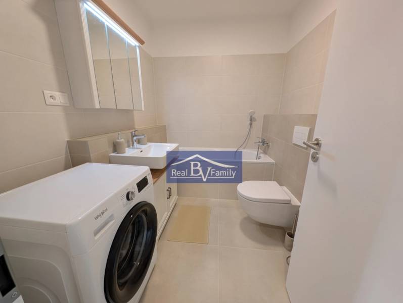 Badezimmer in einer 2-Zimmer-Wohnung mit Waschmaschine, Waschbecken und Badewanne.
