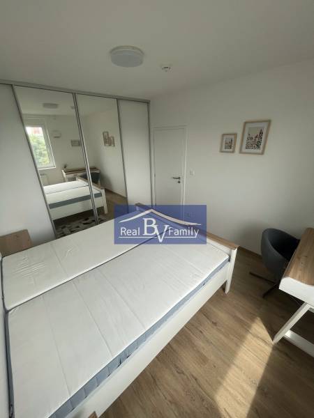 Schlafzimmer in einer Zweizimmerwohnung mit Bett, Kleiderschrank und kleinem Schreibtisch.