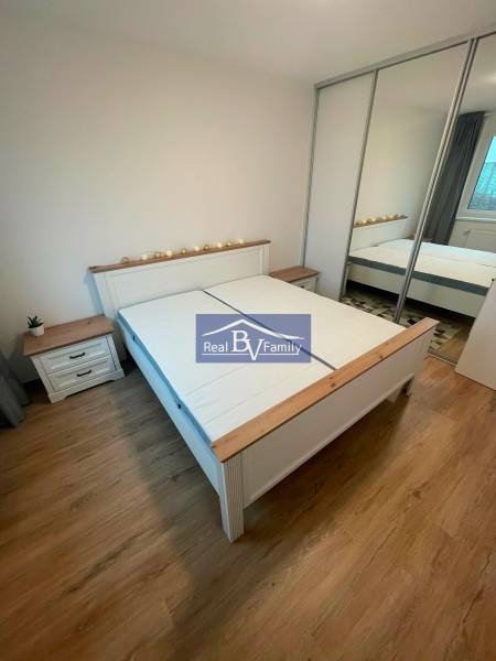 Schlafzimmer in einer 2-Zimmer-Wohnung mit Holzboden, Doppelbett und Einbauschrank.