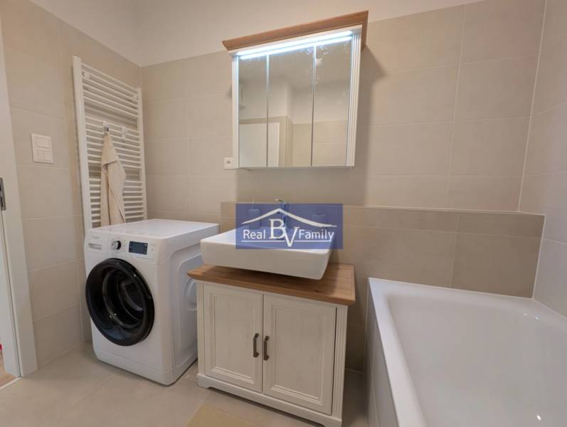 Badezimmer in einer 2-Zimmer-Wohnung mit Waschmaschine, Waschbecken und Badewanne.