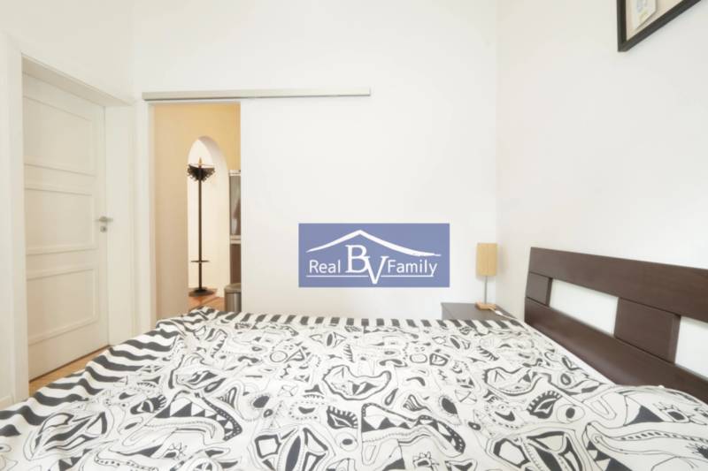 Schlafzimmer mit Doppelbett und gemusterter Bettwäsche in einer 2-Zimmer-Wohnung.