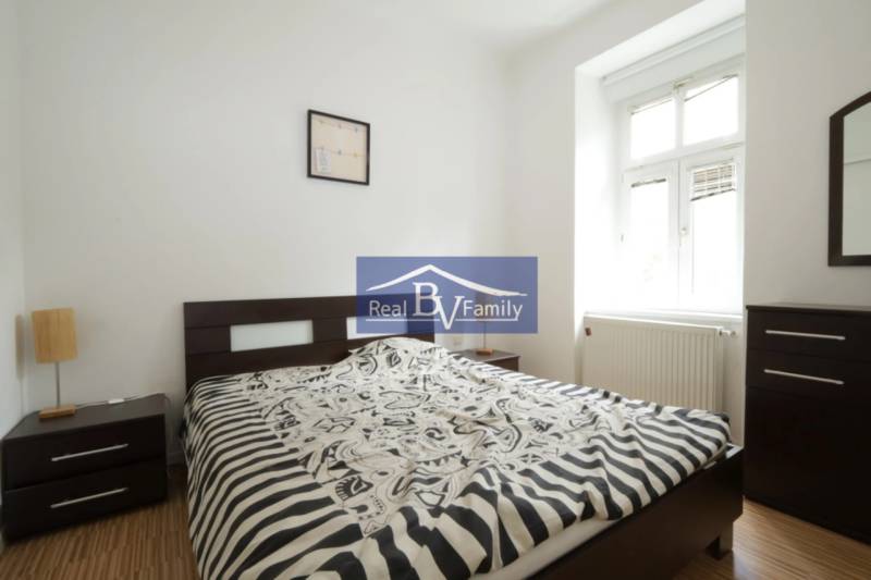 Schlafzimmer mit Bett und Nachttischen in einer 2-Zimmer-Wohnung.