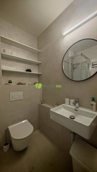 Badezimmer in einer Einzimmerwohnung mit rundem Spiegel, Waschbecken und Toilette.