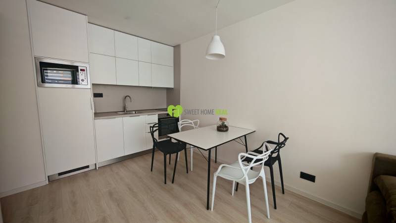 Küche in einer Einzimmerwohnung mit Esstisch und Stühlen, helle Holzböden.